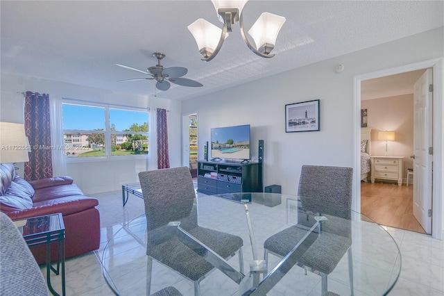 dining space featuring ceiling fan with notable chandelier, light tile patterned flooring, and a textured ceiling