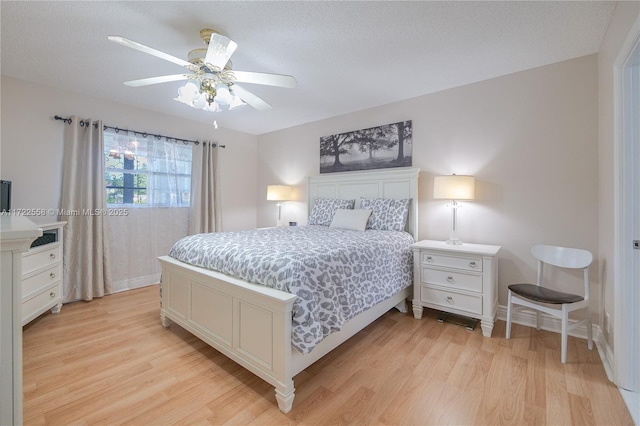 bedroom featuring ceiling fan, light hardwood / wood-style floors, and a textured ceiling