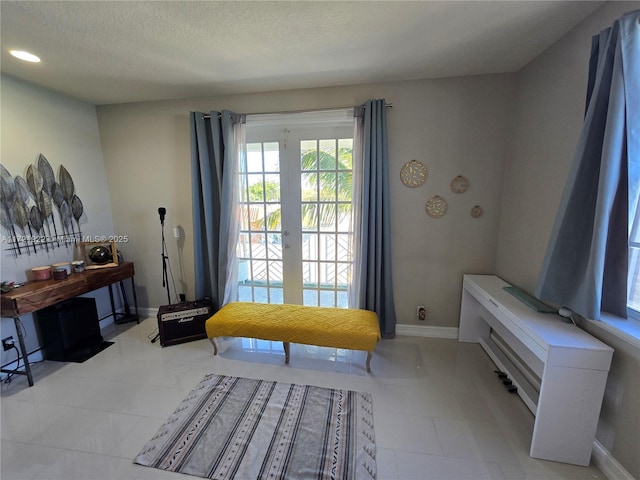 living area with french doors, light tile patterned floors, and a textured ceiling