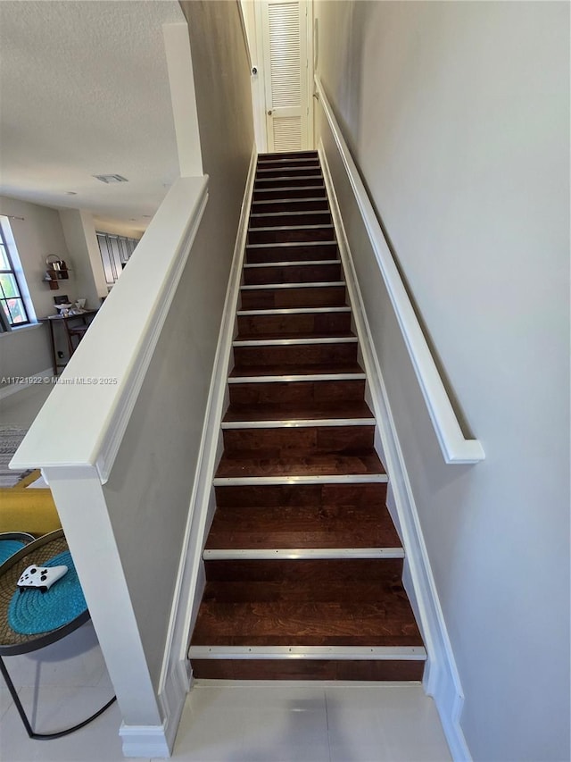 stairway featuring a textured ceiling