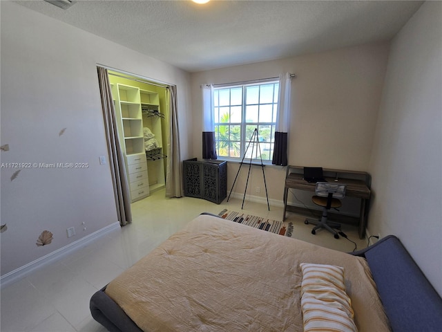 bedroom with a walk in closet, a textured ceiling, and a closet