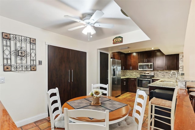 tiled dining area featuring ceiling fan and sink