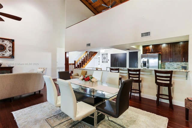 dining area with ceiling fan, a towering ceiling, and dark hardwood / wood-style floors