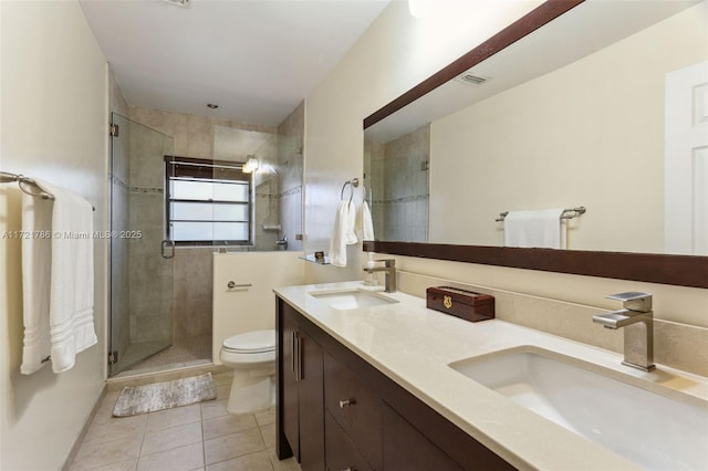 bathroom featuring toilet, vanity, tile patterned floors, and a shower with door