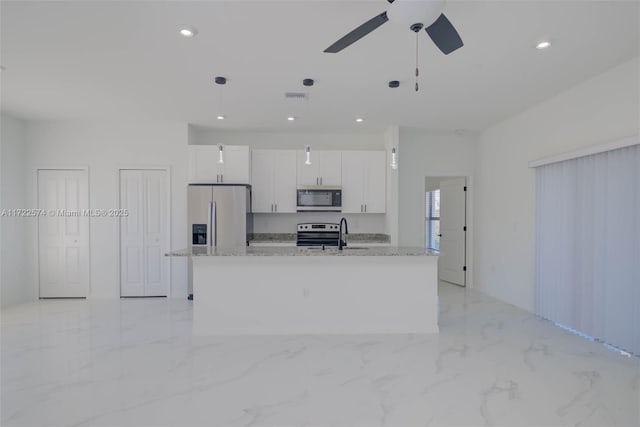 kitchen with a kitchen island with sink, pendant lighting, white cabinets, and stainless steel appliances