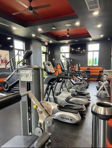 workout area with ceiling fan and a raised ceiling