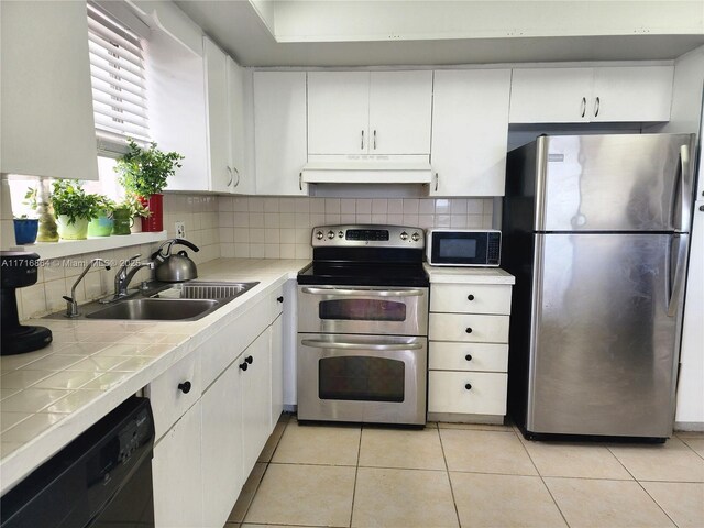 1351 NE Miami Gardens Dr Unit 1025E, Miami, FL 33179 - kitchen with black appliances, under cabinet range hood, tile countertops, a sink, and white cabinets