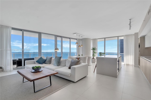 living room featuring light tile patterned floors, rail lighting, and a water view