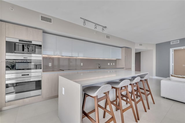 kitchen with a breakfast bar, a center island, black electric stovetop, tasteful backsplash, and light tile patterned flooring