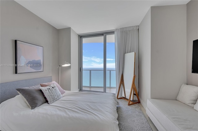 bedroom with access to outside, multiple windows, a water view, and a wall of windows