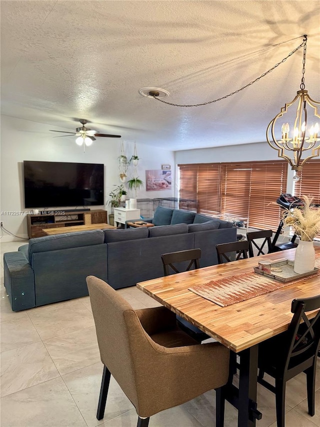 dining area with ceiling fan with notable chandelier and a textured ceiling