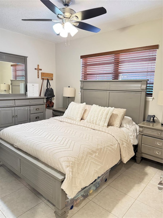 bedroom with ceiling fan, light tile patterned flooring, and a textured ceiling