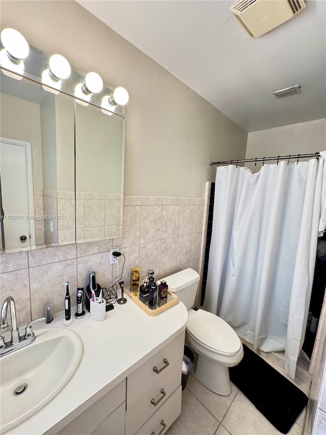 bathroom featuring tile patterned floors, vanity, tile walls, and toilet