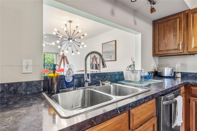 kitchen with dark stone counters, dishwasher, sink, and a chandelier