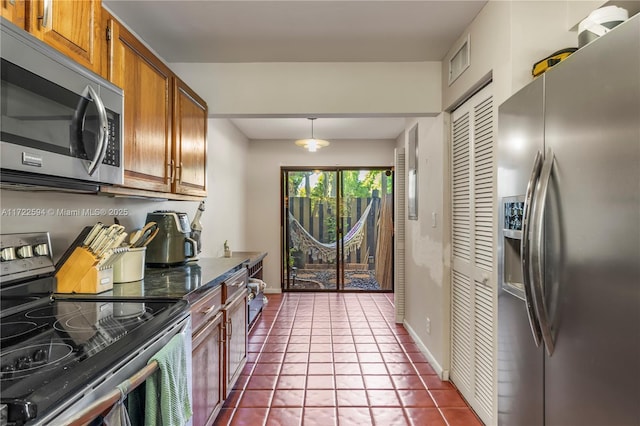 kitchen featuring tile patterned flooring, appliances with stainless steel finishes, and pendant lighting