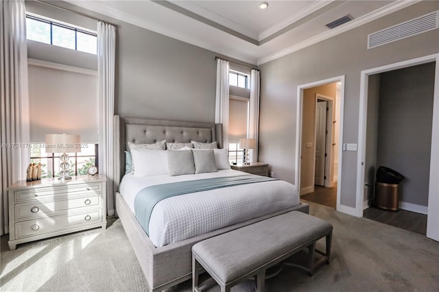 carpeted bedroom with a raised ceiling and ornamental molding