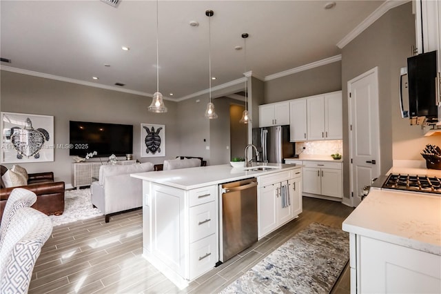 kitchen with a kitchen island with sink, white cabinets, pendant lighting, and appliances with stainless steel finishes