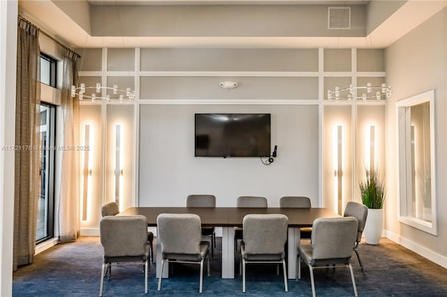 dining area featuring a towering ceiling and dark carpet