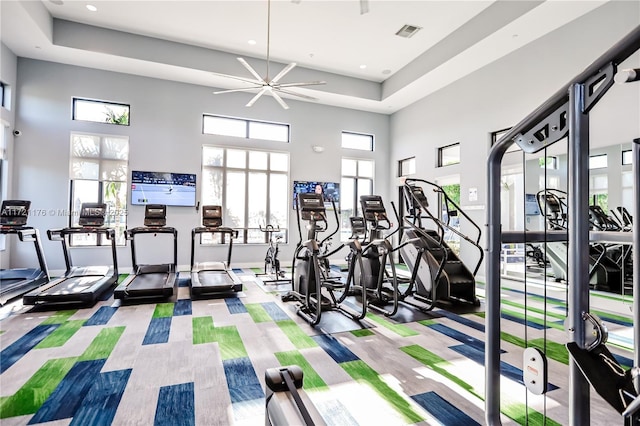 exercise room with ceiling fan and a high ceiling