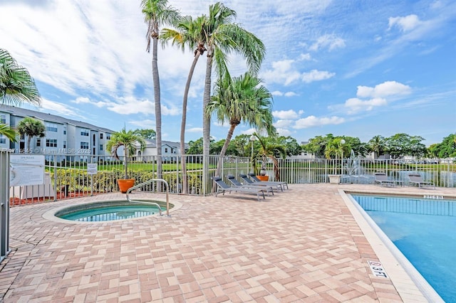 view of pool with a water view, a patio, and a hot tub