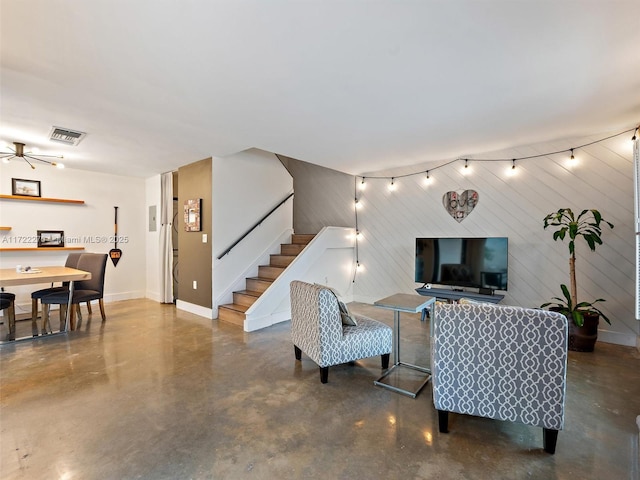 living room featuring concrete floors, wood walls, and ceiling fan