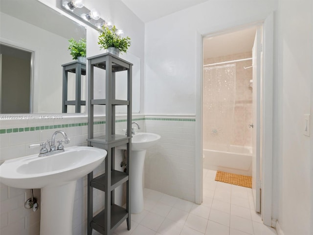 bathroom with tile walls, tile patterned floors, shower / tub combo with curtain, and sink