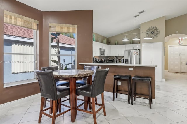 tiled dining room with lofted ceiling