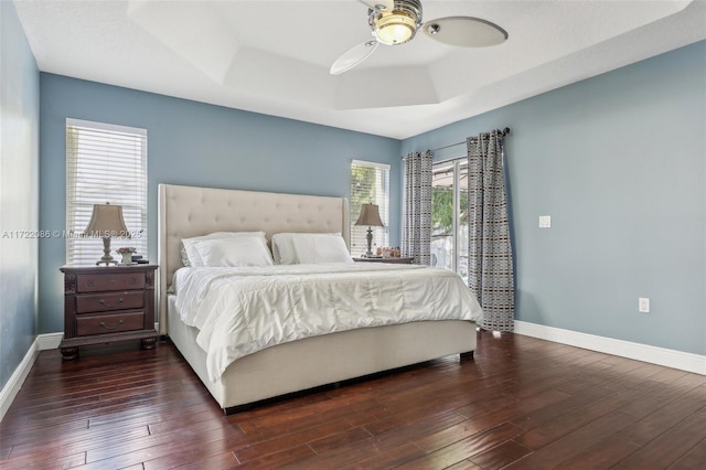 bedroom with ceiling fan, dark hardwood / wood-style flooring, and a raised ceiling