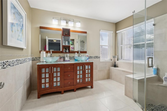 bathroom featuring tile patterned floors, vanity, a shower with door, and tile walls