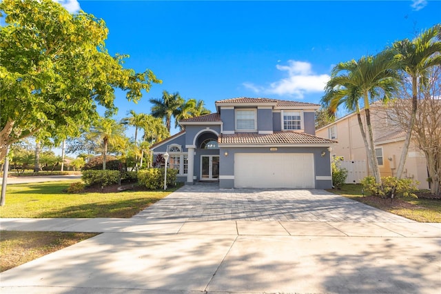 mediterranean / spanish house featuring a front lawn, a garage, and french doors