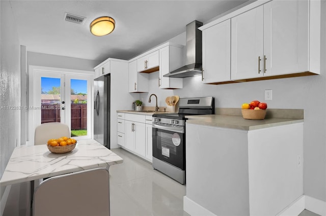 kitchen featuring appliances with stainless steel finishes, sink, white cabinetry, and wall chimney range hood