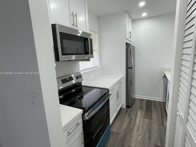 kitchen with light stone counters, dark hardwood / wood-style flooring, white cabinets, and appliances with stainless steel finishes