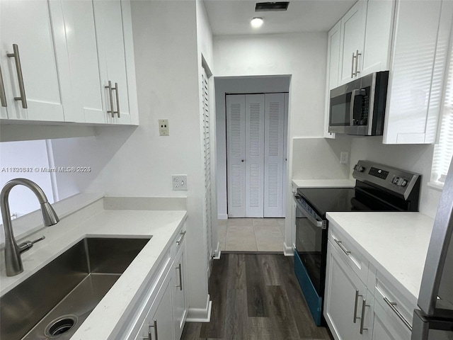 kitchen featuring light stone countertops, stainless steel appliances, sink, white cabinets, and dark hardwood / wood-style floors