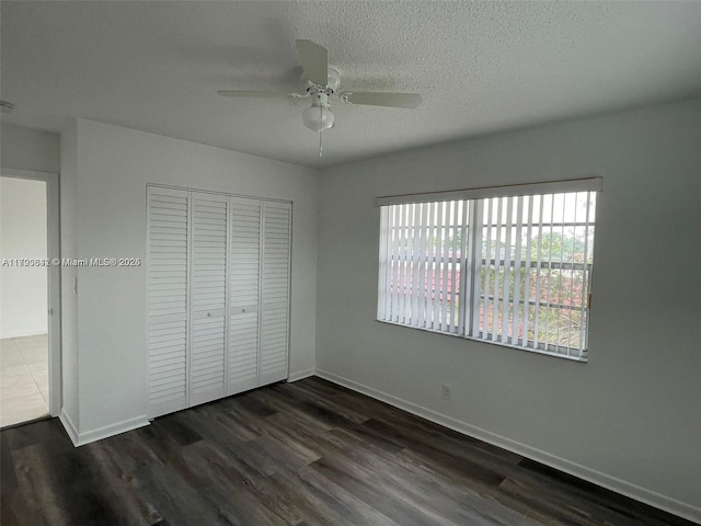 unfurnished bedroom featuring ceiling fan, dark hardwood / wood-style flooring, a textured ceiling, and a closet