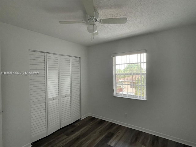 unfurnished bedroom with a textured ceiling, dark hardwood / wood-style flooring, a closet, and ceiling fan