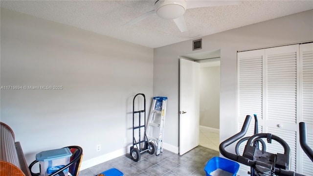 workout area featuring a textured ceiling and ceiling fan