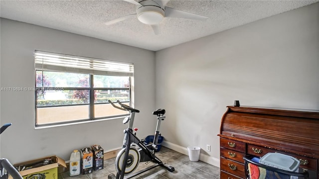 workout area with ceiling fan, light tile patterned floors, and a textured ceiling