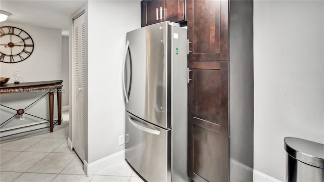 kitchen with light tile patterned floors, dark brown cabinetry, and stainless steel refrigerator