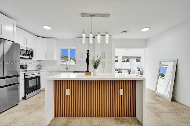 kitchen featuring hanging light fixtures, white cabinetry, appliances with stainless steel finishes, and a center island