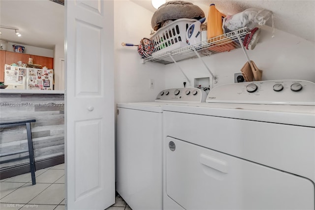 clothes washing area featuring washer and clothes dryer and light tile patterned floors