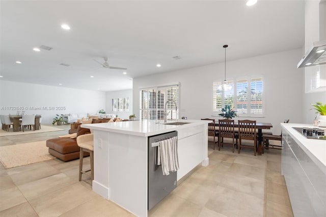 kitchen featuring a kitchen island with sink, ceiling fan, sink, dishwasher, and hanging light fixtures