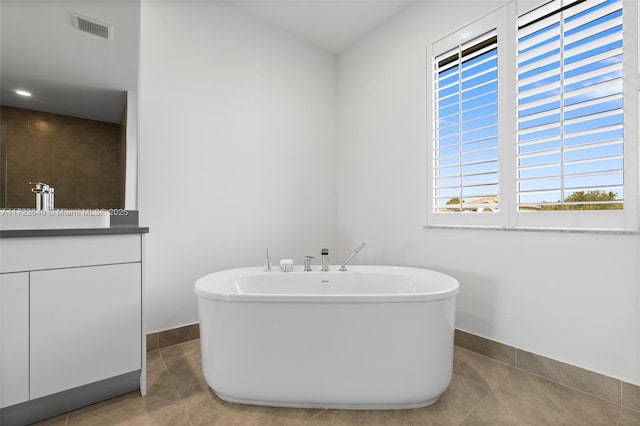 bathroom with a bathtub, vanity, and tile patterned flooring