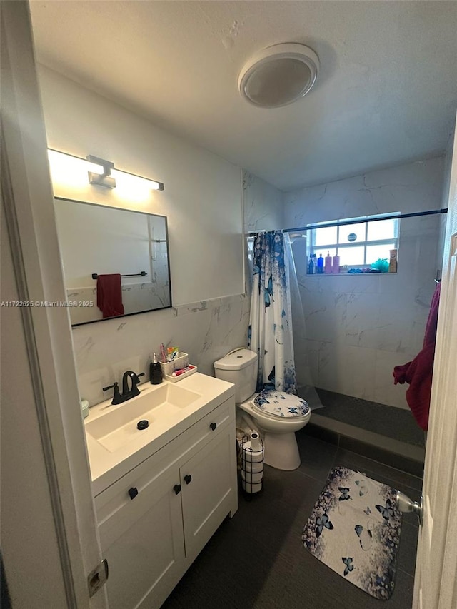 bathroom with vanity, toilet, curtained shower, and tile walls