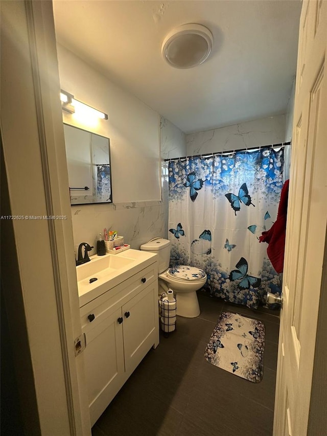 bathroom with toilet, tile walls, walk in shower, and vanity