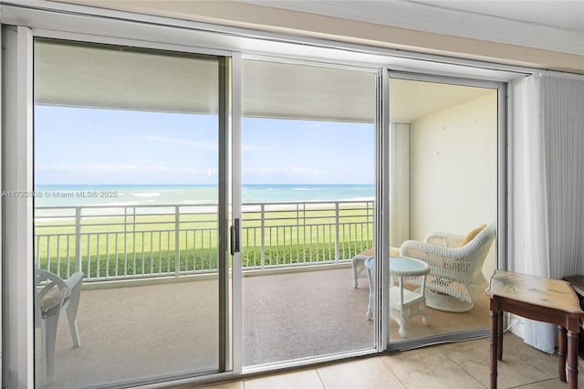 entryway with light tile patterned flooring, a water view, and a beach view