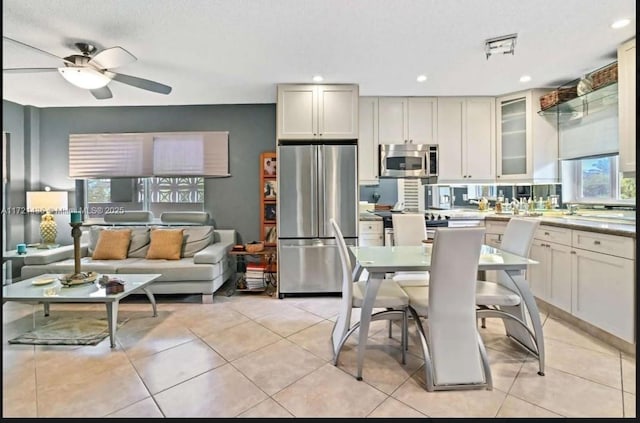 kitchen with a textured ceiling, ceiling fan, light tile patterned flooring, and stainless steel appliances