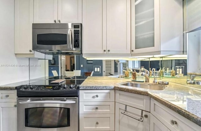 kitchen with light stone countertops, sink, white cabinets, and stainless steel appliances