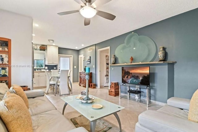 living room with a textured ceiling, ceiling fan, and light tile patterned flooring