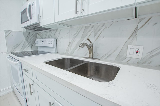 kitchen featuring white appliances, sink, decorative backsplash, light stone countertops, and white cabinetry