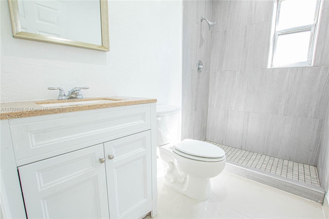 bathroom with a tile shower, vanity, and toilet